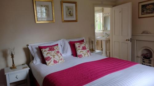 a bedroom with a bed with red and white sheets at Buckley Farmhouse B & B in Sidmouth