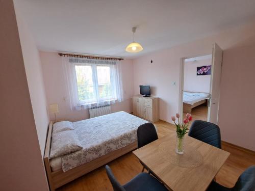 ein Schlafzimmer mit einem Bett und einem Tisch mit Blumen darauf in der Unterkunft Noclegi u Kazi in Polańczyk