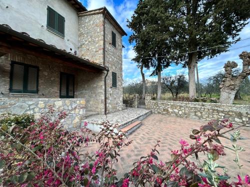 a stone building with a stone wall and some flowers at BORGO A MONTI di Sotto in Gaiole in Chianti