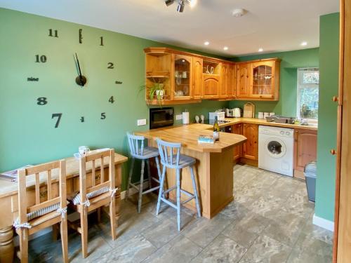 a kitchen with a table and a clock on the wall at Alma Cottage in Borgue