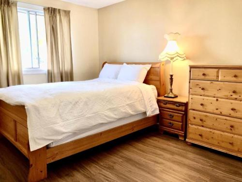 1 dormitorio con 1 cama con cómoda y lámpara en Cheerful Room with private bathroom en Calgary