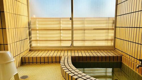 a room with a window and a tub in a bathroom at Kagetsu Ryokan in Shizuoka