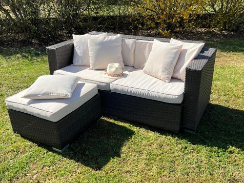 - un canapé en osier avec des oreillers sur gazon dans l'établissement La Parenthèse Enchanté, Gîte à la Campagne, à Montgesty