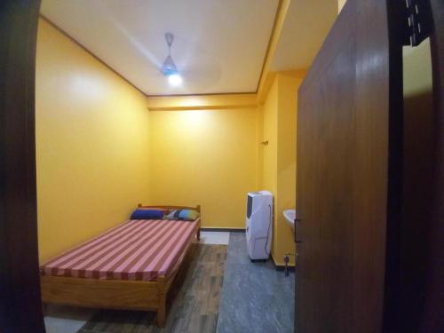 a bedroom with a bed and a yellow wall at Navam in Jaffna