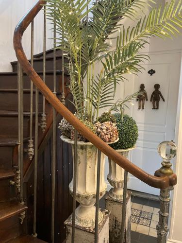 a staircase with a plant in a large vase at Maison Hirondelles Hôtes in Mézières-sur-Issoire