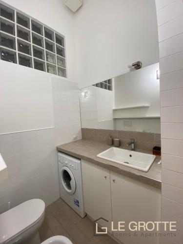 a white bathroom with a washing machine and a sink at Tramonto - Le Grotte Rooms & Apartments in Camerano