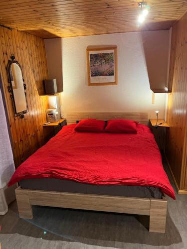 una camera da letto con un grande letto con lenzuola rosse di Au village d'Evolène, très joli studio calme et ensoleillé a Evolène