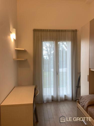 a room with a window with a bed and a desk at Tramonto - Le Grotte Rooms & Apartments in Camerano