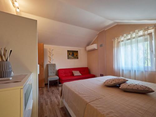 a bedroom with a red bed and a red couch at Villa Neval in Gostinjac