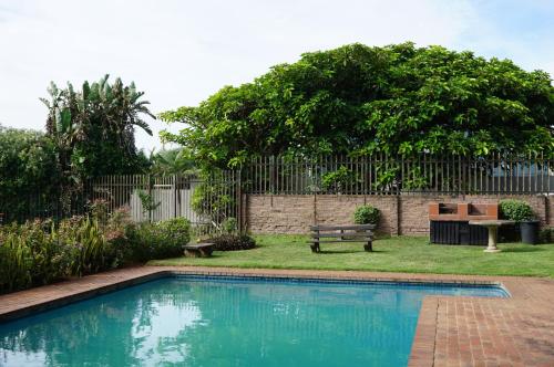 una piscina en un patio con un banco y una valla en 9 Seesonnet Scottburgh, en Scottburgh
