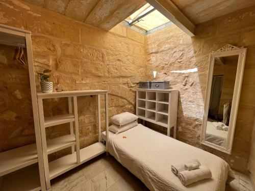 Habitación pequeña con cama y espejo. en Charming 200 year old cottage with yard, en Żabbar