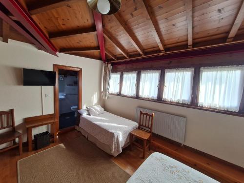 a bedroom with a bed in a room with windows at Hotel La Balsa in Cangas de Onís