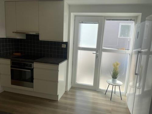 a kitchen with white cabinets and a door with a plant on a stool at 3 rooms apartment in Center in Ålesund