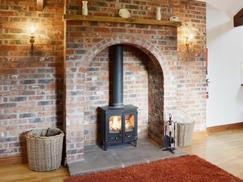 a brick fireplace with a stove in a room at Greengage in Lissett