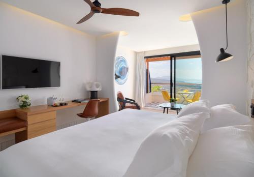 a white bedroom with a bed and a television at H10 Atlantic Sunset Horizons Collection in Adeje