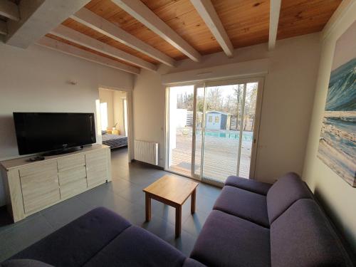 ein Wohnzimmer mit einem Sofa und einem TV in der Unterkunft Maison à Tosse avec vue sur la nature in Tosse