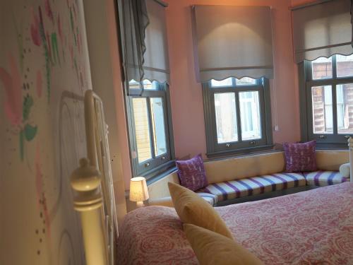 a bedroom with a bed and a couch and windows at Tilas - Rooms in 19th Century Wooden Townhouse,Kadikoy in Istanbul