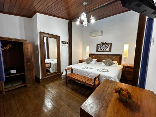 a bedroom with a bed and a table and a mirror at Hotel Ponta do Morro in Tiradentes