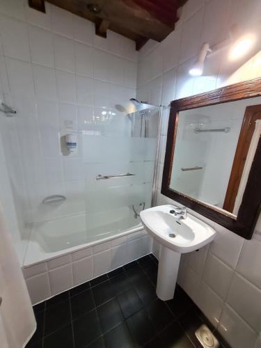 a white bathroom with a sink and a shower at Hotel La Balsa in Cangas de Onís