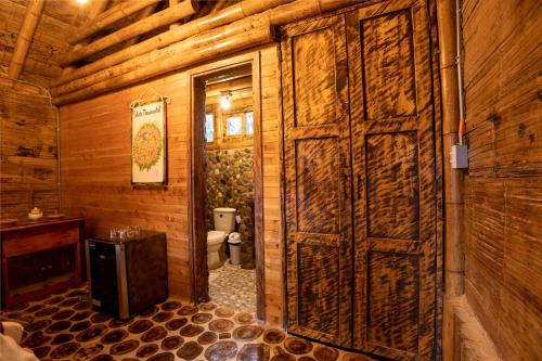 baño de madera con aseo y puerta de madera en Jardin de los Silleteros Agro Parque Hotel, en Santa Elena