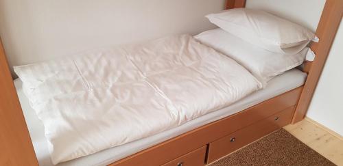 a bed with white sheets and pillows on it at Hortenzia Vendégház Márianosztra in Márianosztra