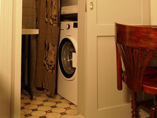 a laundry room with a washing machine and a chair at Tilas - Rooms in 19th Century Wooden Townhouse,Kadikoy in Istanbul
