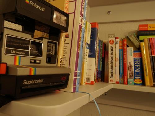 acomputer sitting on a shelf in front of books at Tilas - Rooms in 19th Century Wooden Townhouse,Kadikoy in Istanbul