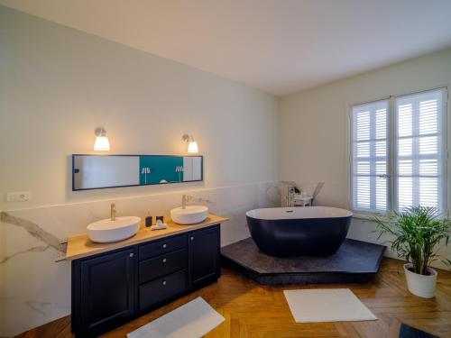 un bagno con due lavandini e una grande vasca di Aux Marquises a Saumur
