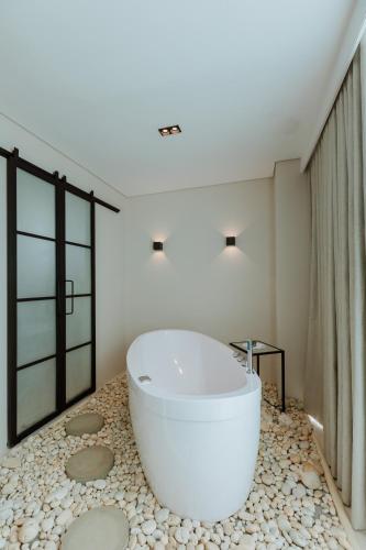 a bathroom with a large white tub on a stone floor at 1616 Hotel in Medellín
