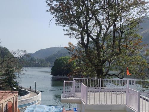 a view of a river with a white fence and a tree at The Periwinkle Homestay Bhimtal in Bhīm Tāl