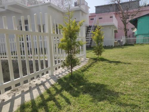 a white picket fence in front of a house at The Periwinkle Homestay Bhimtal in Bhīm Tāl