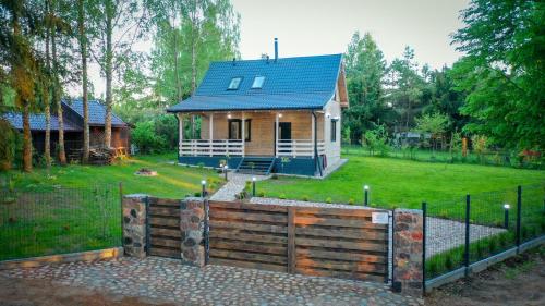 une petite maison avec une clôture devant elle dans l'établissement Mazury domek nad jeziorem z jacuzzi, à Szczytno