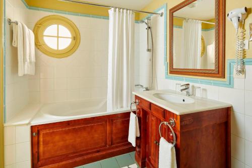 ein Badezimmer mit einem Waschbecken, einer Badewanne und einem Spiegel in der Unterkunft 2 Bedrooms Apartment at Village D'ile De France in Bailly-Romainvilliers