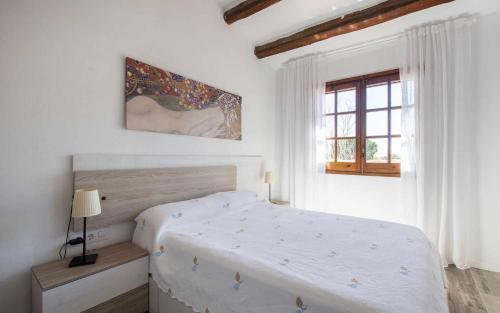 Habitación blanca con cama y ventana en Casas Blanca 34 piscina Playa privada wifi, en Tossa de Mar