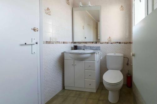 uma casa de banho com um WC, um lavatório e um espelho. em Casas Blanca 34 piscina Playa privada wifi em Tossa de Mar
