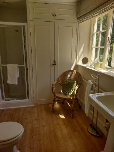 a bathroom with a chair and a toilet and a sink at Buckley Farmhouse in Sidmouth