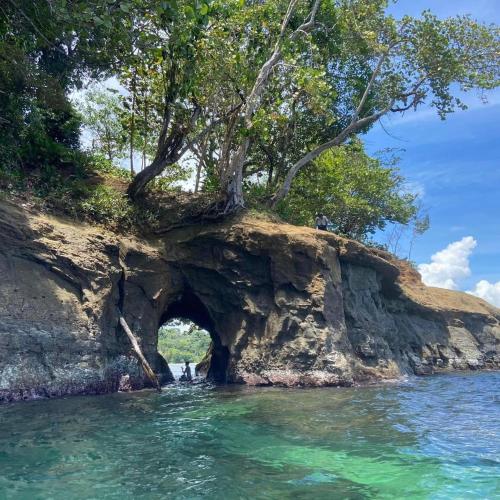 a cave in the side of a rocky island in the water at Cabinas Manzanillo Caribe in Manzanillo