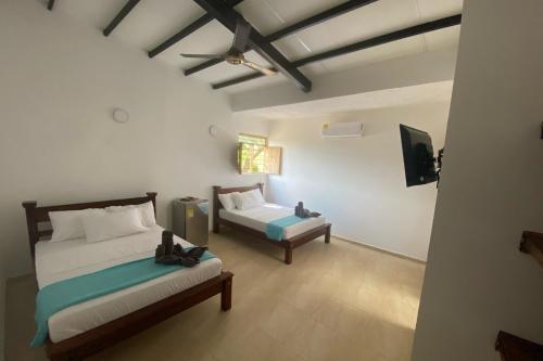 een slaapkamer met 2 bedden en een tv. bij Hotel Ayenda Palmas del Río in Mompós