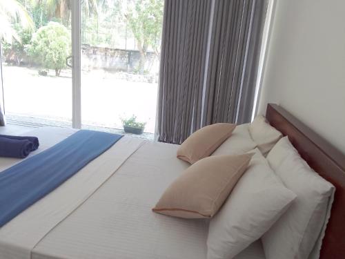 a bedroom with a bed with pillows and a window at Savendro Villa Hikkaduwa in Hikkaduwa