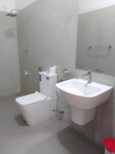a white bathroom with a toilet and a sink at Savendro Villa Hikkaduwa in Hikkaduwa
