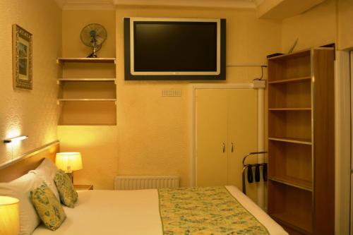 a bedroom with a bed and a tv on the wall at Falcon Hotel in London