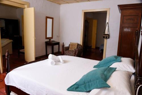 una camera da letto con un grande letto bianco con cuscini verdi di Casa típica Salamineña a Salamina