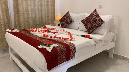 uma cama branca com cobertores e almofadas vermelhos e brancos em Kiwengwa Minazi Resort em Kiwengwa