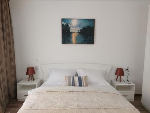 a bedroom with a white bed with two lamps at Casa EMMA in Jurilovca