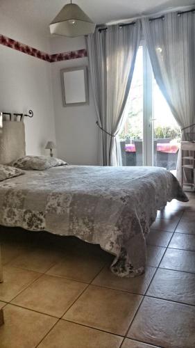 une chambre avec un grand lit et une fenêtre dans l'établissement Chambres d'Hôtes dans villa avec piscine chez Raphaële, à LʼIsle-sur-la-Sorgue