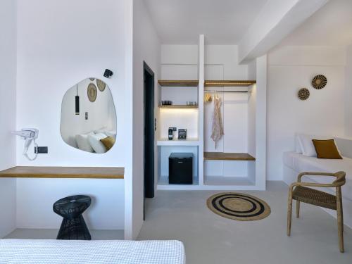 a white bedroom with a bed and a room with a chair at Paros Five Senses in Parikia