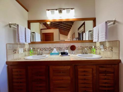 a bathroom with two sinks and a large mirror at Bella Sway Belize in Placencia