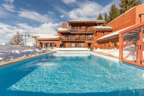 une grande piscine devant un immeuble dans l'établissement Cocon à la Plagne, à Plagne 1800