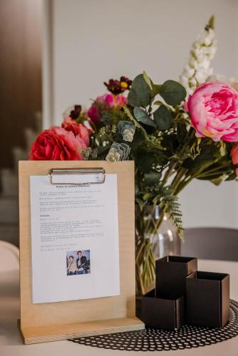 a sign sitting on a table next to a vase of flowers at Viktoria Guesthouse in Westerlo