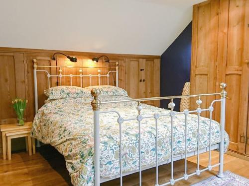 a bedroom with a bed with a floral bedspread at Last Barn in Saint Twynnells